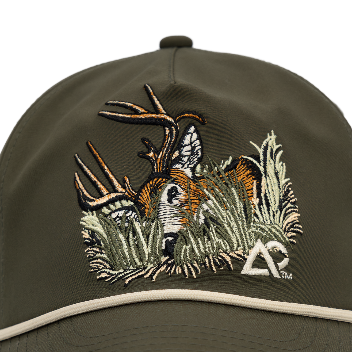Closeup of Faded olive hat with deer on front in foliage, with white Archery Country logo