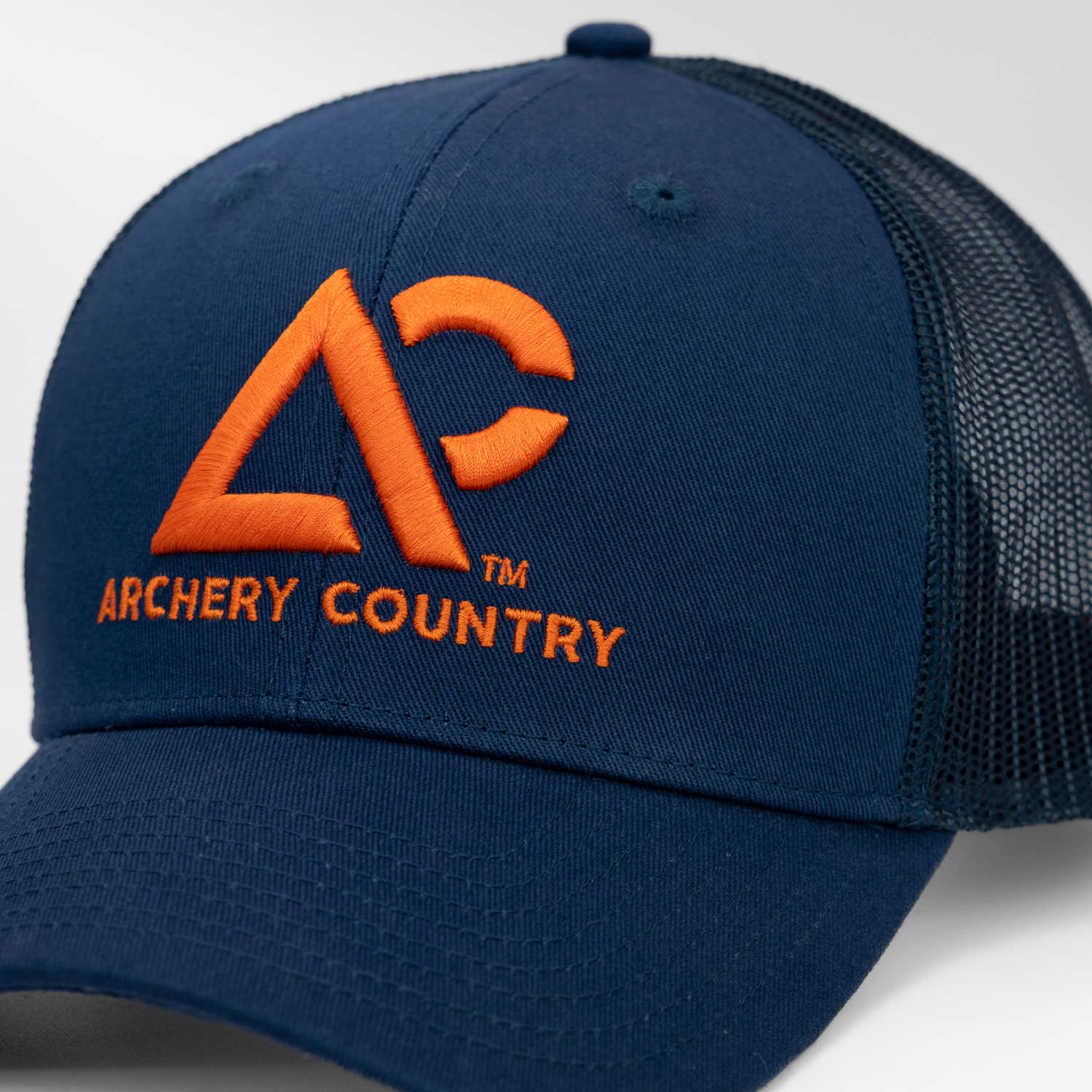 Closeup of navy meshback cap with "ARCHERY COUNTRY" logo on front in orange