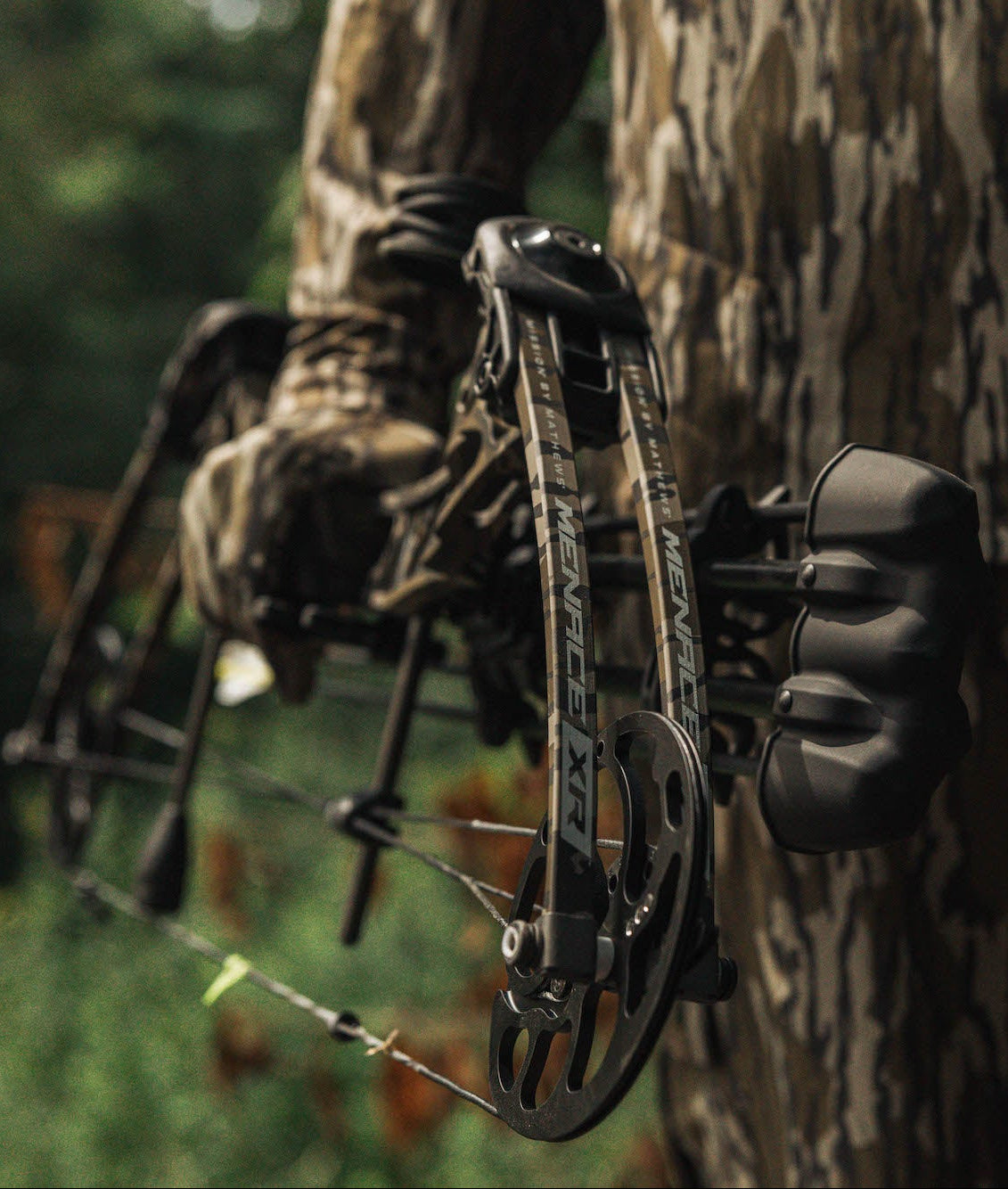 Person in camouflage holding a bow and arrow in a forest setting