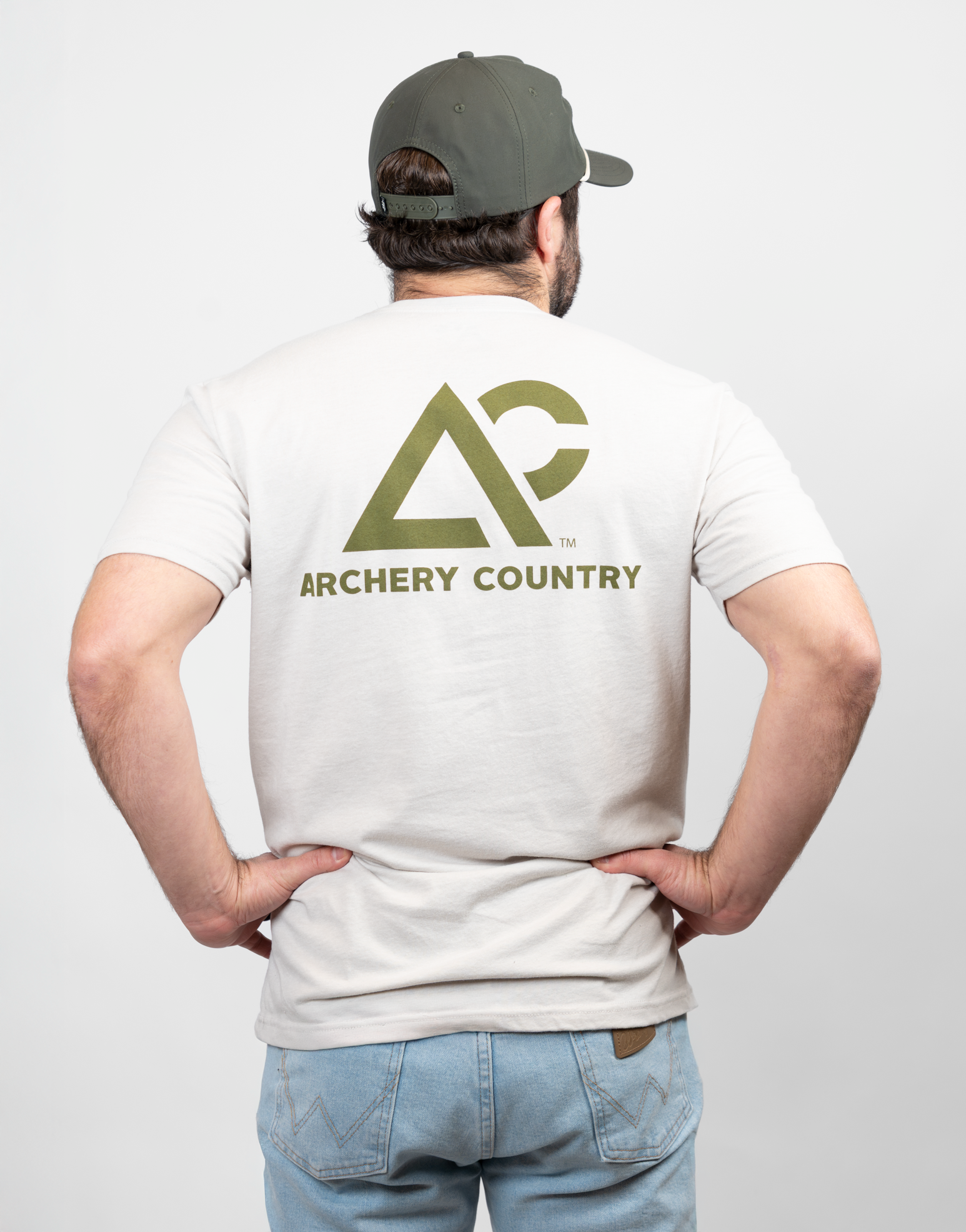 Rear view of man wearing heather sand tee with "Archery Country" logo on back