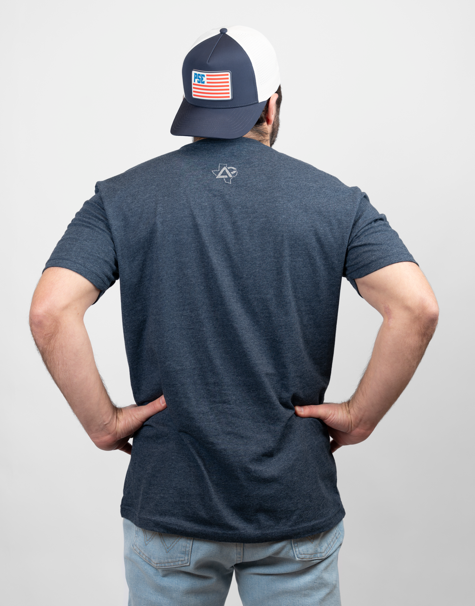 Rear view of man wearing heather navy shirt with Texas Archery Country logo on upper back