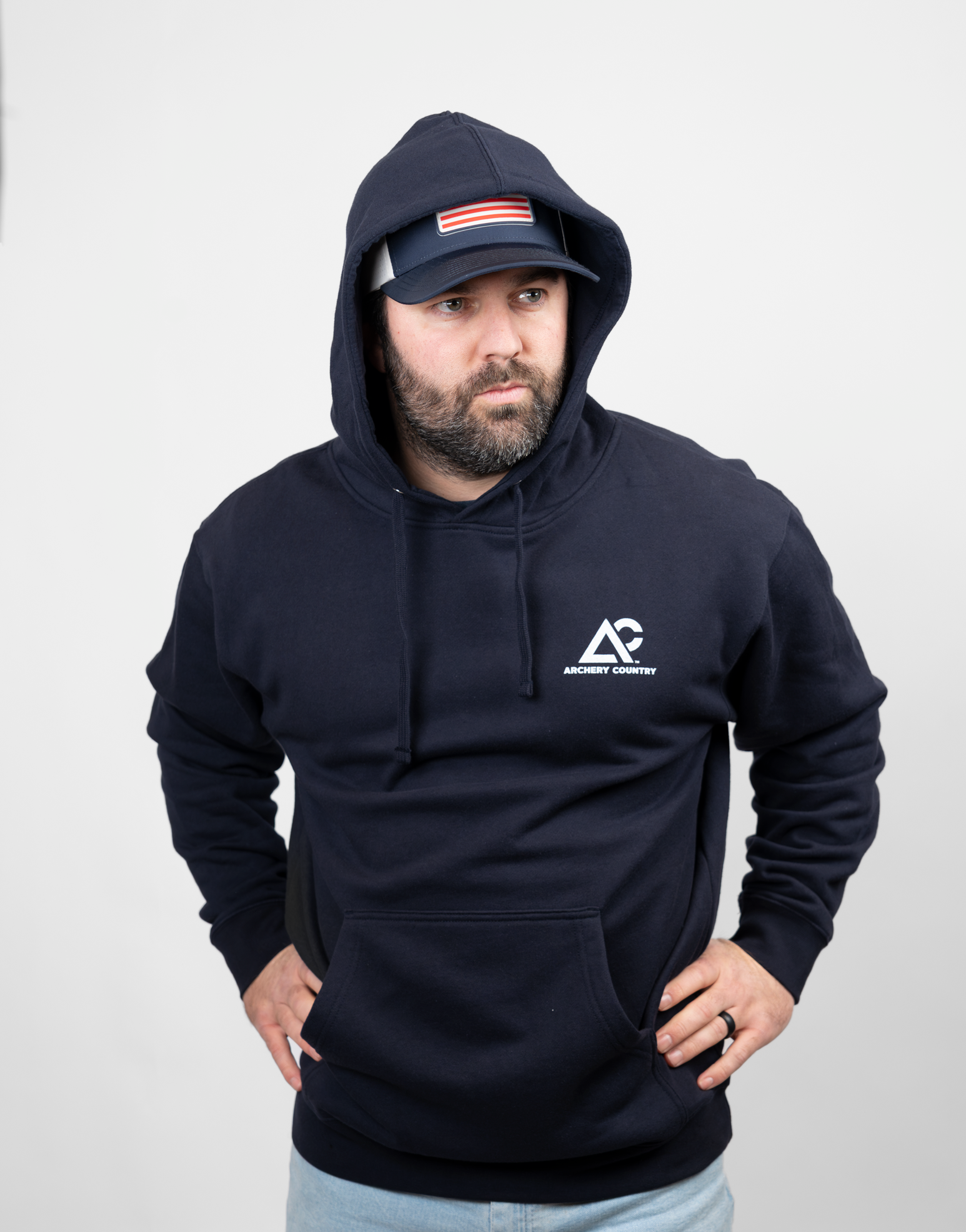 man wearing navy hoodie with hood up with white Archery Country logo on left chest