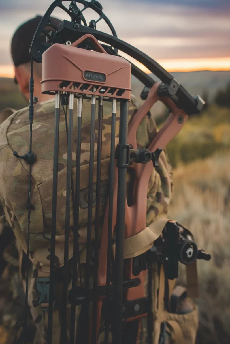 Person wearing a crossbow on their back in an outdoor setting